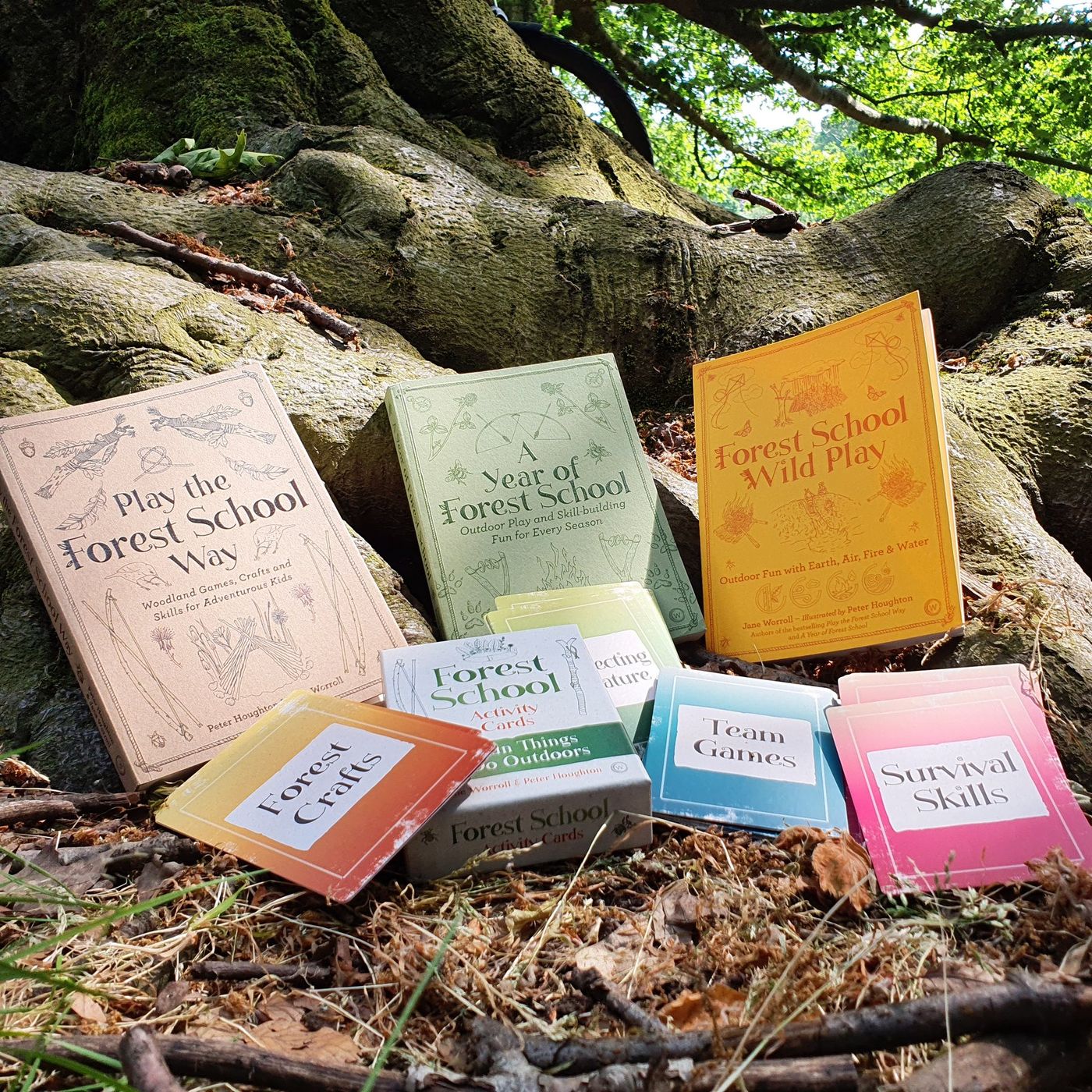 Forest School books and activity cards arranged at the base of a tree