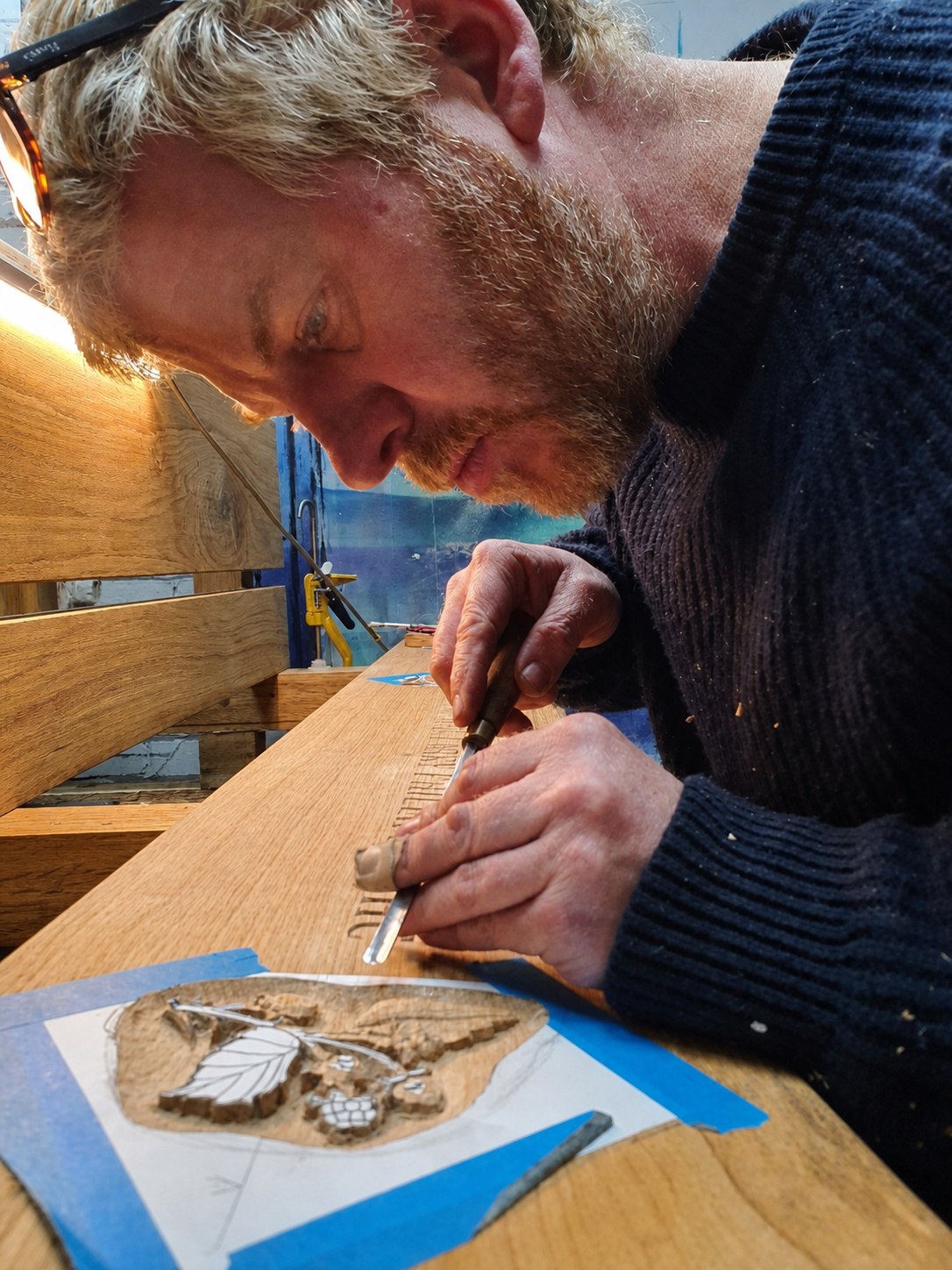 Peter Houghton carving a wooden bench in the workshop
