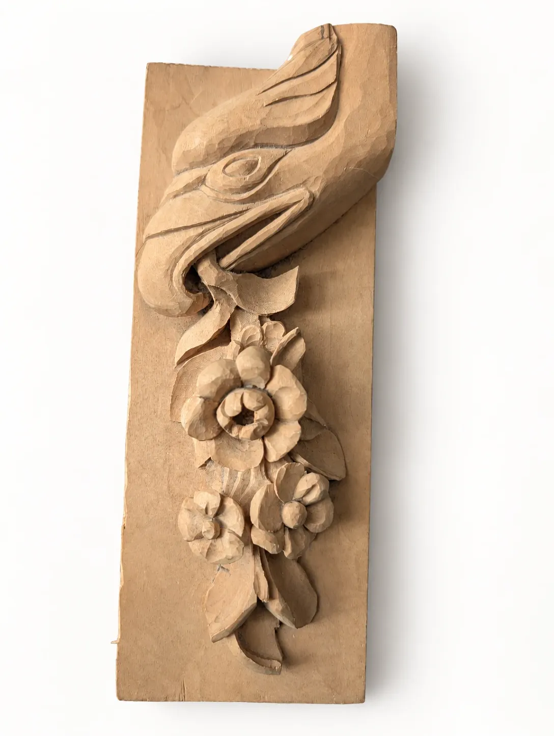 Upright view of the carved eagle head above the flowers on its wooden board