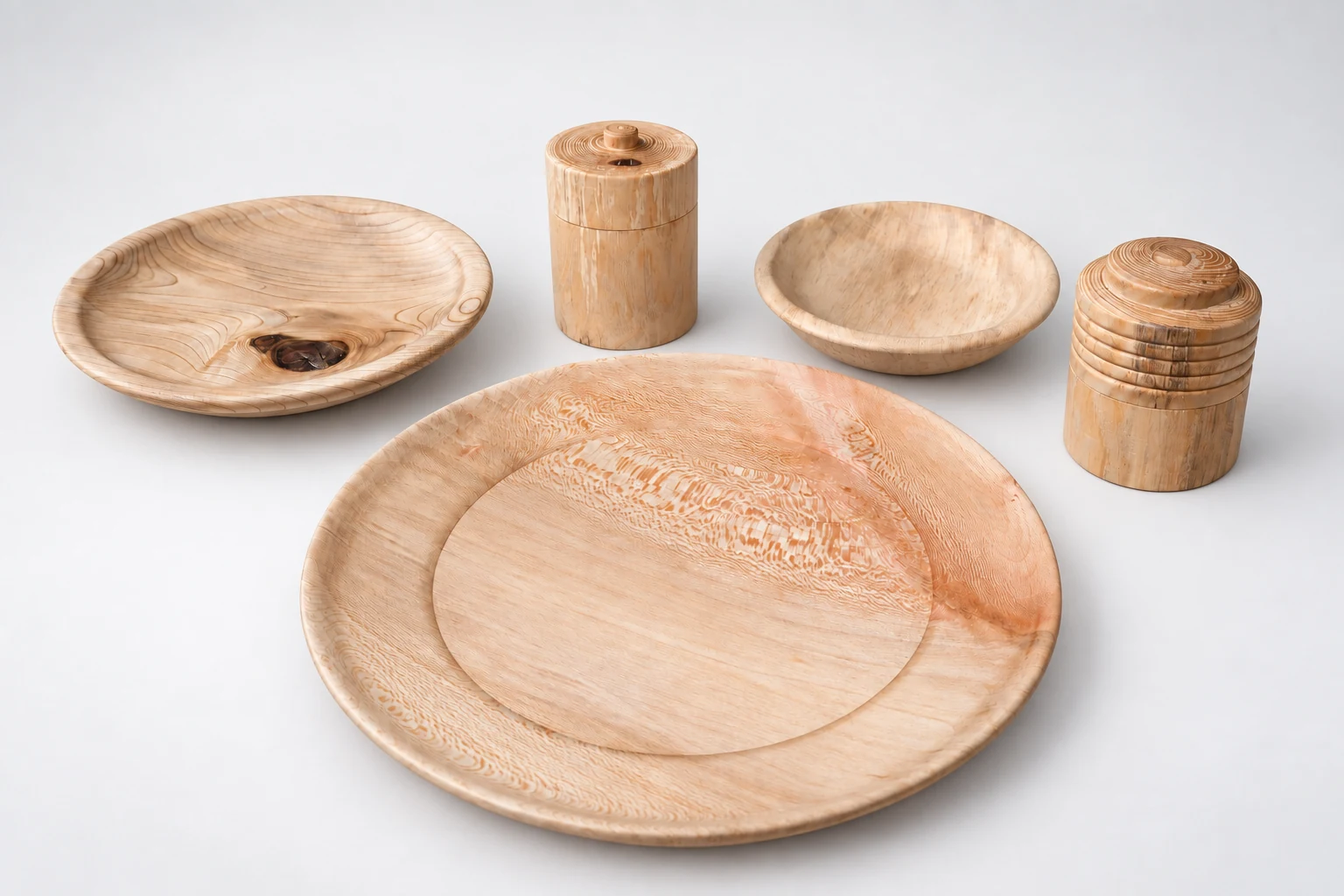 Wooden plates, bowls and lidded vessels arranged against a white background