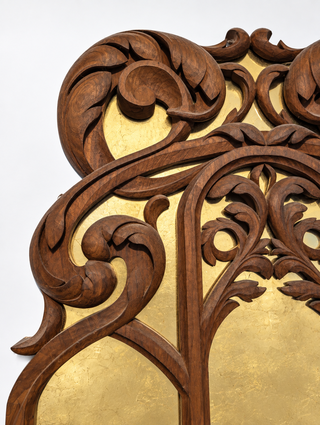 Close detail of the walnut scroll carving and gold leaf behind the glass