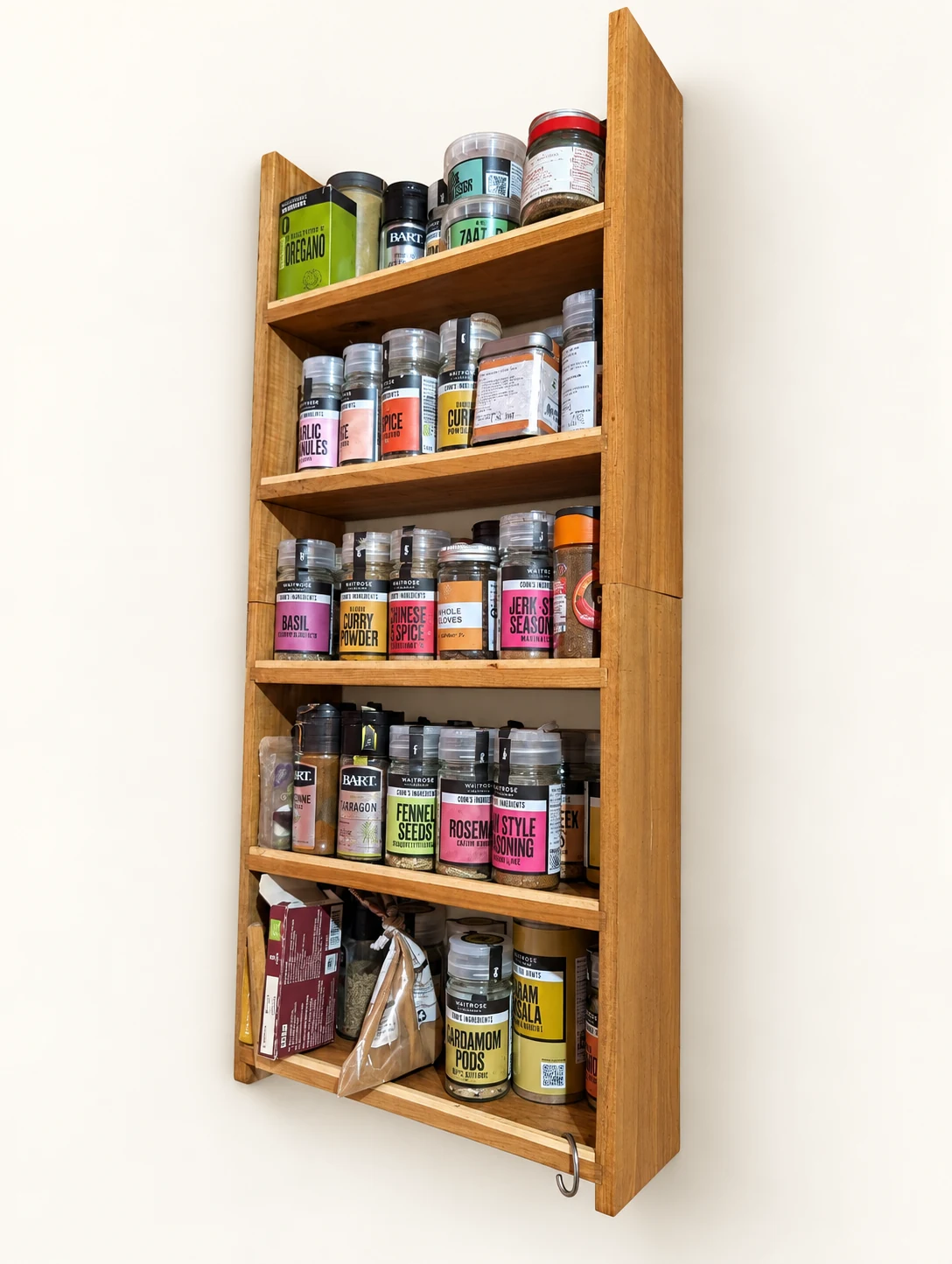 Handmade wooden spice rack filled with spice jars on an off-white background